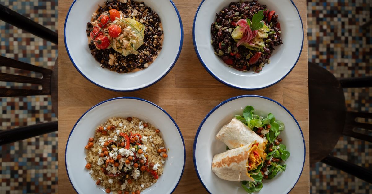 Top view of four healthy grain and vegetable bowls on a wooden table, perfect for nutritious meal ideas.