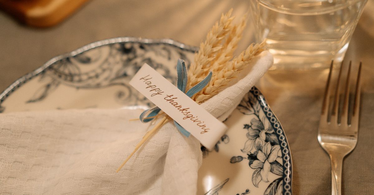 Beautiful Thanksgiving table setting with decorated plate and napkin featuring wheat and a festive greeting card.