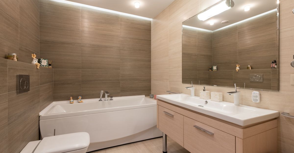 A contemporary bathroom featuring a bathtub, dual sinks, and ambient lighting.