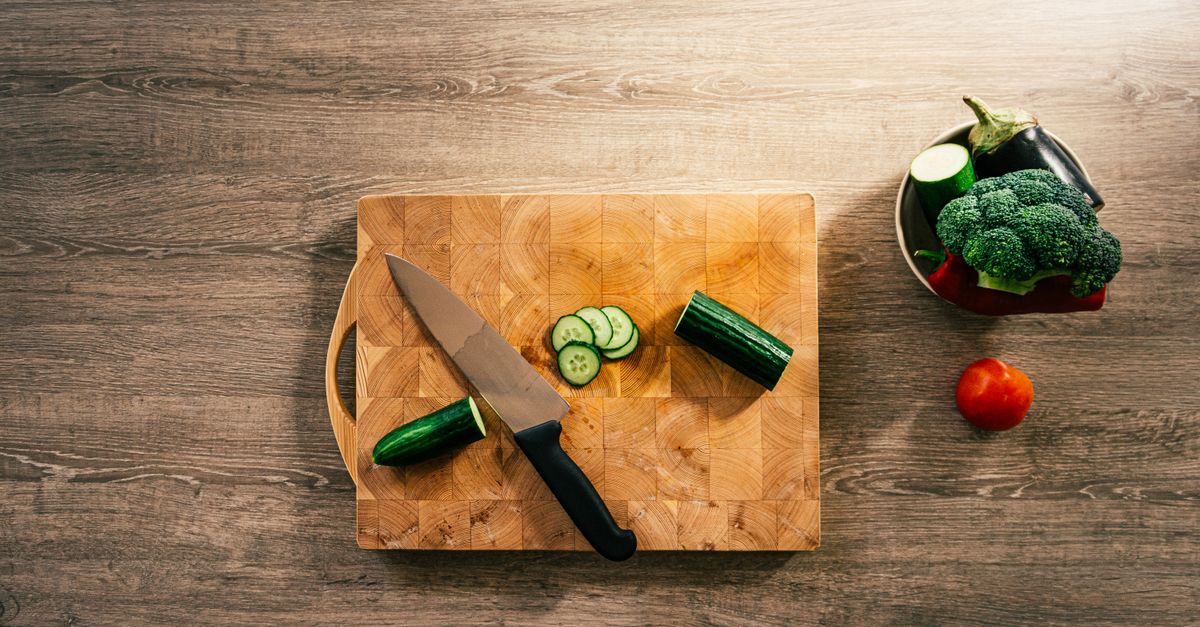 Top-down view of fresh vegetables and knife on wooden board, perfect for healthy lifestyle concepts.